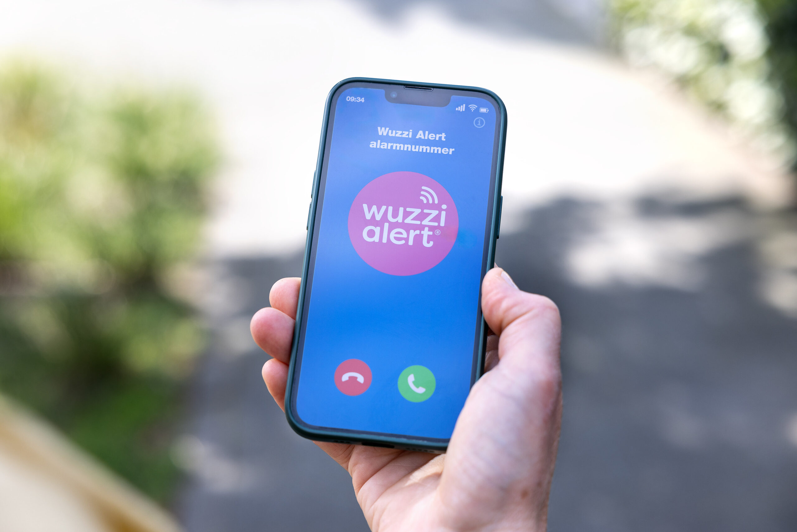 hand heeft mobiele telefoon vast waarop een alarmoproep van het Wuzzi Alert alarmnummer op binnenkomt